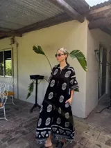 Vestido largo negro con estampado de flores blancas, mangas cortas y corte amplio.