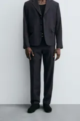 Pantalón de vestir negro de corte relaxed fit confeccionado en tejido con lana. Cuenta con bolsillos frontales y traseros de doble vivo con botón. Cierre frontal con cremallera y botón.