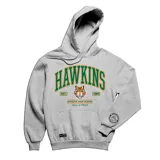 Canguro gris con capucha y bolsillo delantero tipo canguro. Estampado frontal con el nombre "Hawkins" en letras verdes con borde naranja, un tigre y el texto "Est. 1983" y "Emexem High School".