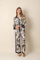Conjunto de camisa y pantalón de seda sintética color crema con estampado floral en tonos azul marino y detalles en azul marino en cuello, mangas y laterales del pantalón.