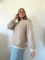 Sweater beige tejido a mano con lana y terminaciones en crochet con hilo de seda. Tiene cuello redondo, mangas ranglan balloon y silueta recta con aberturas laterales.