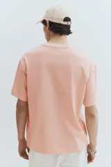 Remera color salmón de corte holgado, cuello redondo y manga corta. Estampado frontal con la frase "Currently Unavailable".