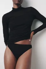 Top semitransparente tipo jersey confeccionado en hilatura de algodón 100%. Cuello alto y manga larga.