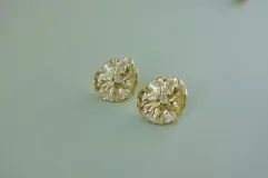 Aros tipo botón dorados con textura irregular que simula la superficie de un molusco.