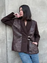 Chaqueta marrón de lana tejida con paneles de cuero texturizado, cuello acanalado, cierre con hebilla dorada y bolsillos laterales.