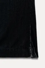 Pantalón de terciopelo negro de tiro medio con cintura elástica, bolsillos laterales ocultos y pierna ancha.