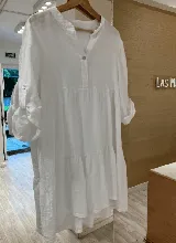 Vestido corto blanco de lino con cuello mao, manga larga con botón para sujetar y corte escalonado.