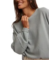 Remera de manga larga color gris con textura acanalada, cuello redondo, hombros caídos, puños y costuras marcadas con terminaciones sin rematar.