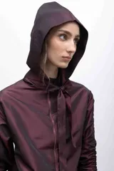 Capucha deportiva color borgoña, confeccionada en tafeta tornasolada con tiras ajustables que pueden anudarse formando un lazo.