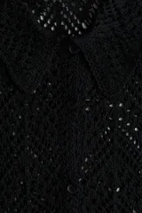 Camisa negra de manga corta en punto pointelle suave, con cuello y botones adelante. Ribete festoneado en mangas y bajo.