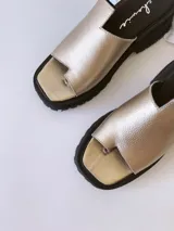 Sandalias doradas con tira para el dedo y suela track negra.
