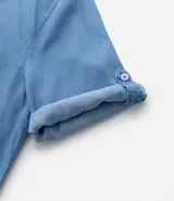 Vestido corto estilo chemise color celeste, con cuello en pico tipo solapa, mangas 3/4 con ajuste, bolsillos laterales y ajuste holgado.