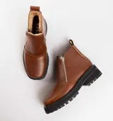 Bota de cuero vacuno color marrón, con interior forrado en corderito natural. Tiene suela de goma artesanal, punta cuadrada, cierre YKK en ambos lados y caña de 11cm.