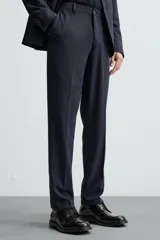 Pantalón de vestir azul marino, de corte slim fit, confeccionado en tejido con 17% de lana. Cuenta con bolsillos frontales y traseros de doble vivo con botón. Cierre frontal con cremallera y botón.