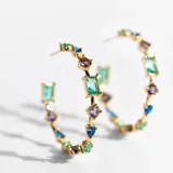 Aros dorados en forma de argolla abierta, adornados con cristales en tonos multicolor.