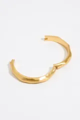 Pulsera rígida plateada de metal con textura irregular y cierre de bisagra.