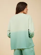 Sweater color crema con degradé a naranja, con cuello redondo y logo estampado de palmera en el pecho.