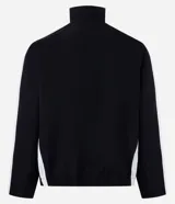 Campera deportiva negra con cuello alto y cierre frontal. Presenta franjas blancas contrastantes a lo largo de las mangas y detalles gráficos en blanco en el pecho, incluyendo la palabra "GUILTY" en grande.