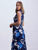 Vestido largo de seda fría con estampado floral en tonos azul y blanco. Tiene escote en V cruzado, cintura con faja plisada y detalles con relieve.