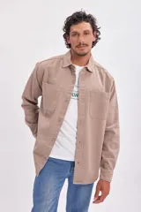Sobrecamisa color beige con cuello camisero, cierre frontal con botones a presión, dos bolsillos de parche en el pecho y mangas largas con puños abotonados.