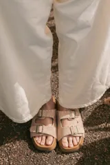 Sandalia de gamuza color beige con doble tira, tachas y hebillas metálicas.