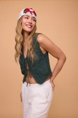 Chaleco corto tejido a crochet color verde oliva, con escote en V y cierre frontal con lazos.