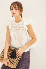 Camisa blanca de algodón con detalles de puntilla en el canesú y volados con terminación de puntilla en las mangas.