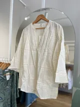 Blusa blanca de algodón con bordado tipo broderie, escote en V y mangas 3/4.