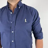 Camisa azul marino a rayas verticales, de corte clásico con cuello italiano y mangas largas con puños abotonados.