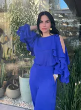 Blusa azul con escote redondo, mangas largas con aberturas en los hombros y volados en los brazos.