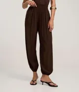 Pantalón de mujer color marrón oscuro, estilo balloon o bombacho, con cintura y puños elásticos.