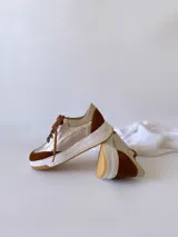 Zapatillas de cuero metálico con detalles en gamuza, cierre de cordones y suela gruesa.