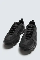 Zapatillas deportivas color crema con cordones, suela gruesa con diseño irregular y detalles en gris.