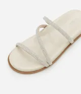 Sandalia plana mule color crema con punta redonda y tiras finas con brillos.