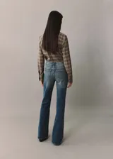 Pantalón de jean acampanado de tiro alto, color azul denim, con cinco bolsillos y trabillas.