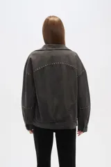 Campera de jean celeste con cuello clásico, solapas, cierre frontal con botones metálicos y mangas largas con puños abotonados. Presenta detalles de costuras diagonales y apliques de tachas metálicas.