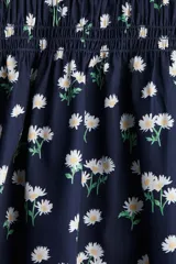 Vestido corto de popelina azul marino con estampado de pequeñas flores blancas, escote cuadrado con elástico fino sobre los hombros, mangas cortas abullonadas con fruncido elástico, cuerpo ajustado fruncido y falda con vuelo. Ribete de volado en escote y puños.