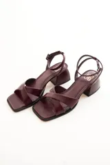 Sandalias plateadas de cuero, con tiras cruzadas sobre el empeine, pulsera al tobillo con hebilla y taco bajo cuadrado.