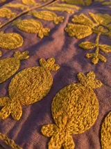 Chaqueta color morado con bordados dorados, cuello mao y corte recto.