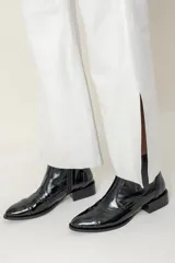 Bota corta de cuero vacuno color negro charol, con elástico lateral, punta fina y detalles de calado.