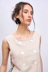 Chaleco celeste con diseño cruzado y doble botonadura, sin mangas y con apliques de encaje en los laterales.