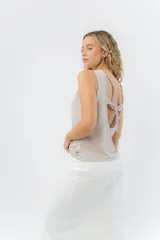 Musculosa color rosa metalizado, sin mangas, confeccionada en lino metalizado, con escote cerrado al frente y espalda abierta con lazo ajustable.