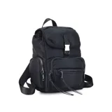 Mochila negra de nylon con tapa y broche metálico. Tiene apertura superior con broche, bolsillos internos, bolsillo con cierre metálico al frente y laterales. Tiene asas rígidas de mano y correas regulables para colgar en la espalda.