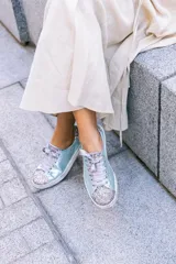 Championes celestes con glitter multicolor en punta y talón, lazo de raso y suela de cuero.