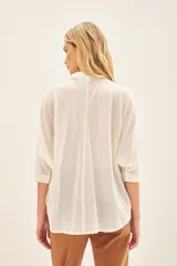 Camisa blanca de voile con rayas finas, corte amplio, cartera con botones y bordado de flores en el frente.