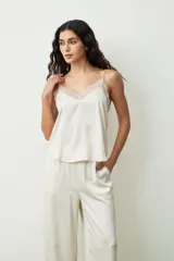 Blusa color crudo con lunares dorados, breteles finos y escote en V con detalle de encaje.