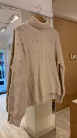 Sweater polerón color beige con cuello alto y diseño de ochos.