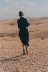 Vestido camisero midi negro con cuello camisero, botonadura frontal, mangas raglán cortas, elástico en la parte posterior de la cintura, frunces adelante y atrás, y cinturón extraíble para atar.