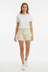 Short de jean color beige claro, tiro alto, con roturas sutiles y terminación desflecada en el ruedo.