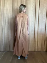 Vestido largo color crudo, sin mangas y con escote en V. Presenta aberturas laterales en el ruedo y bolsillos laterales a la altura de la cadera.